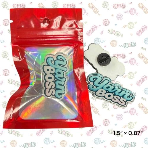 Yarn Boss pin, A red resealable pouch containing a holographic iridescent patch with the words 'Yarn Boss' in stylized lettering, shown next to a matching flat patch on a white patterned background. A small printed size note reads 1.