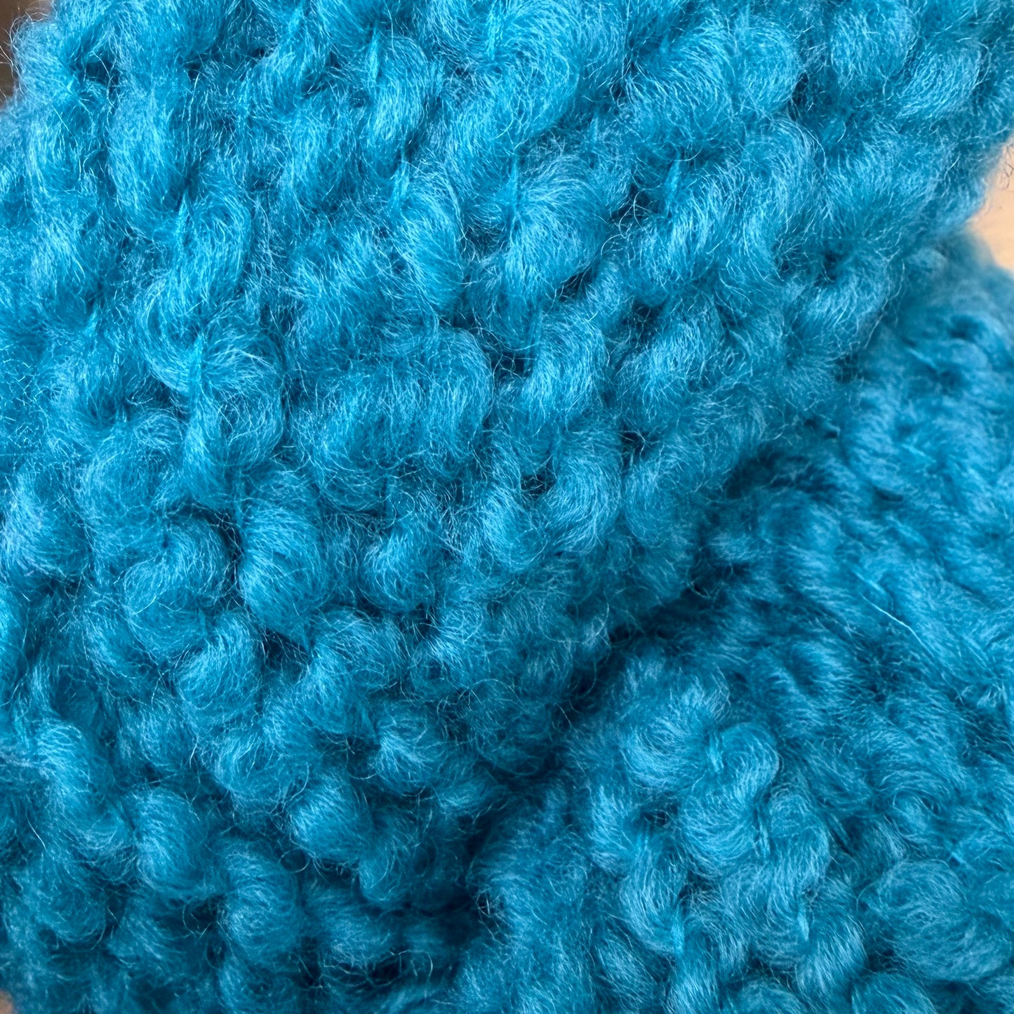 Hokuto by Apple Fiber Studio - A close-up of bright turquoise blue curly knit fabric, showing the detailed texture of the yarn and stitches.