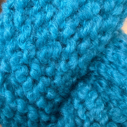 Hokuto by Apple Fiber Studio - A close-up of bright turquoise blue curly knit fabric, showing the detailed texture of the yarn and stitches.