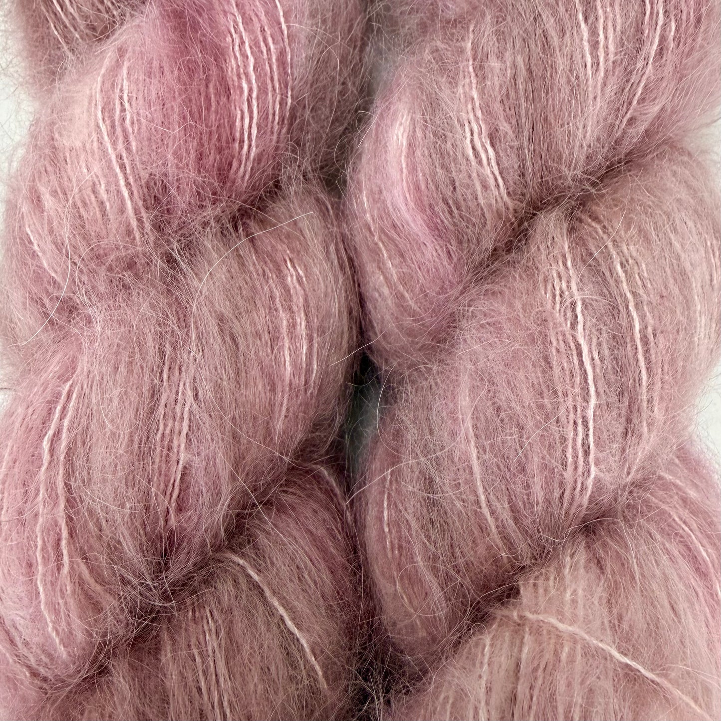 Close-up of soft, fuzzy yarn or fiber in a dusty pink color with subtle lighter pink and white streaks, filling the frame. Hand-dyed Cortland by Apple Fiber Studio in Alpaca and Silk at Apple Yarns.