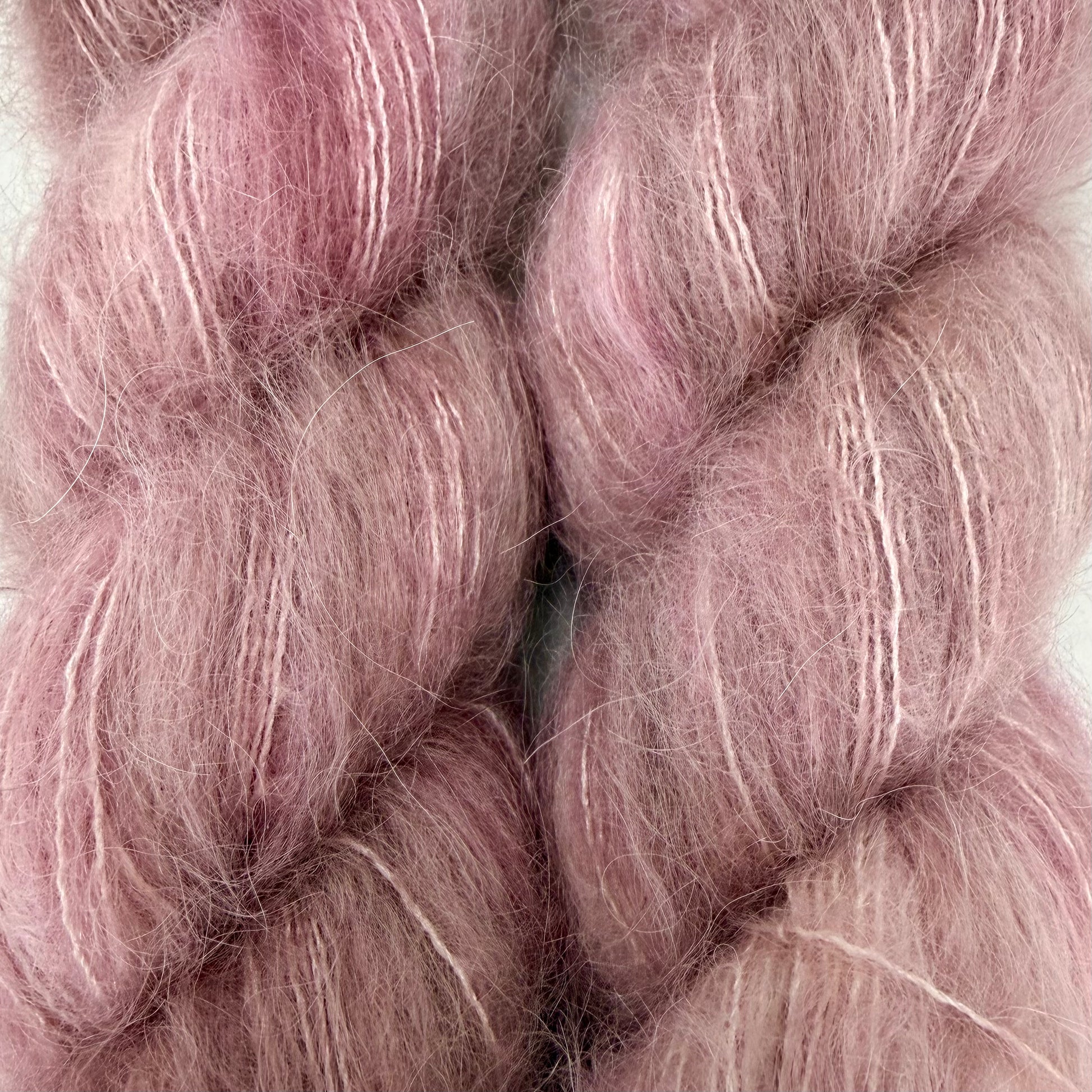 Close-up of soft, fuzzy yarn or fiber in a dusty pink color with subtle lighter pink and white streaks, filling the frame. Hand-dyed Cortland by Apple Fiber Studio in Alpaca and Silk at Apple Yarns.