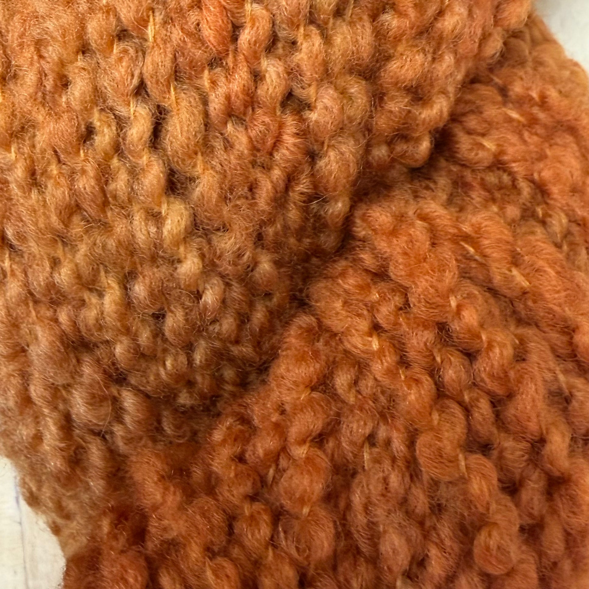 Hokuto by Apple Fiber Studio - Close-up of a chunky knit fabric in a warm rust orange color, showing the detailed texture of the yarn.