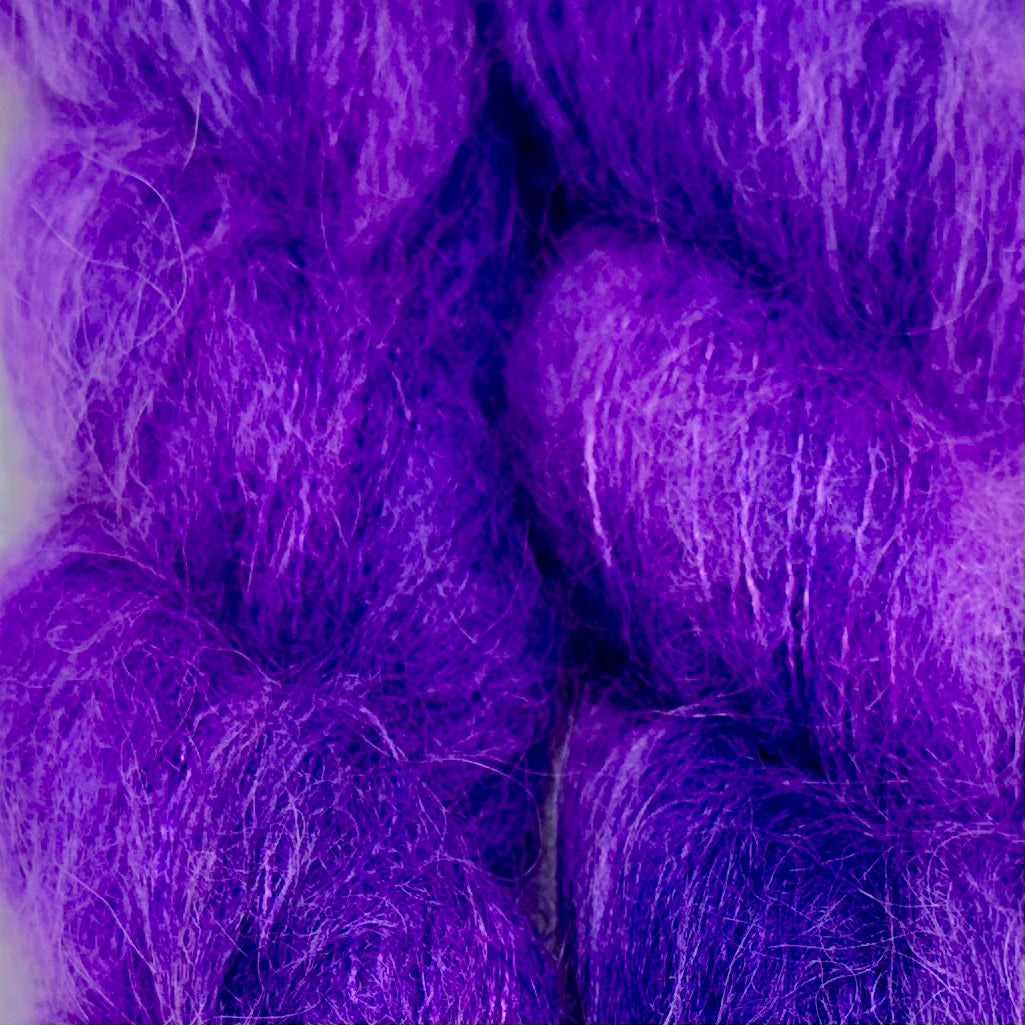 Close-up of fluffy purple and violet fiber strands filling the frame, with no person, animal, or real environment visible. Hand-dyed Cortland by Apple Fiber Studio in Alpaca and Silk at Apple Yarns.