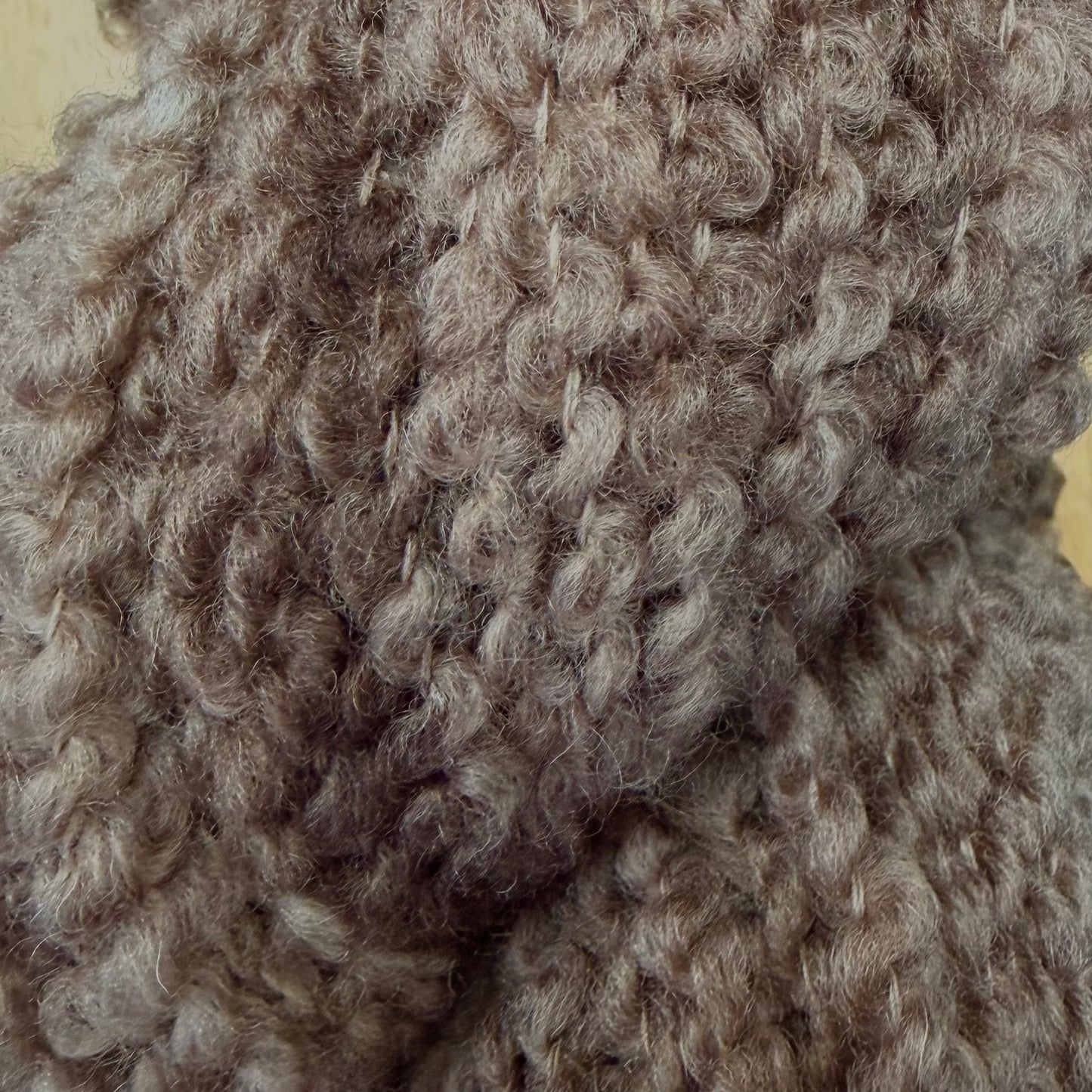 Hokuto by Apple Fiber Studio - Close-up of a chunky, curly knit fabric in a warm taupe-brown color, showing the detailed texture of the yarn.