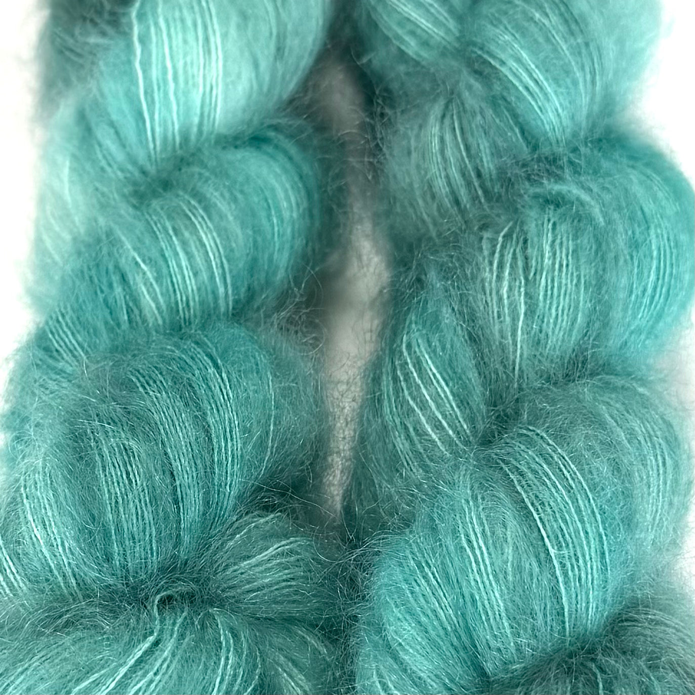 Delicious by Apple Fiber Studio. A close-up of fluffy, twisted yarn in a bright aqua or turquoise shade, filling the frame against a white background.
