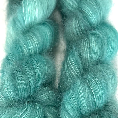 Delicious by Apple Fiber Studio. A close-up of fluffy, twisted yarn in a bright aqua or turquoise shade, filling the frame against a white background.