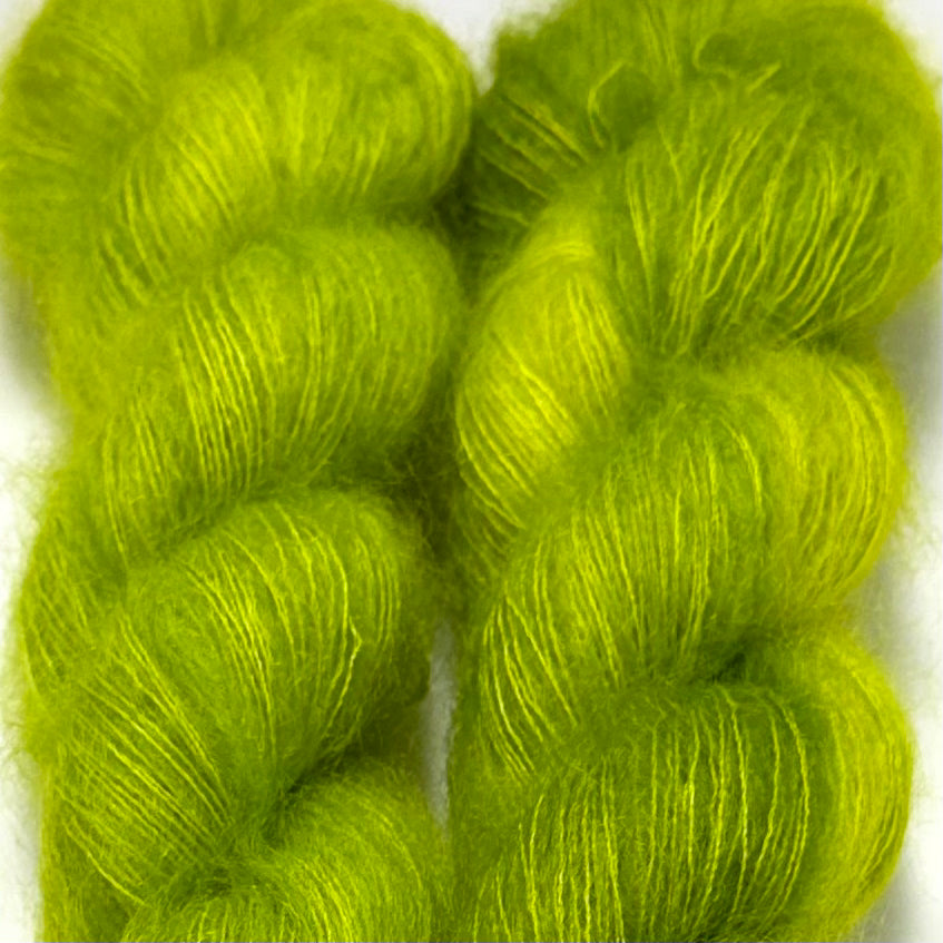Delicious by Apple Fiber Studio. Two bright lime green hanks of fuzzy yarn tightly cropped against a white background.