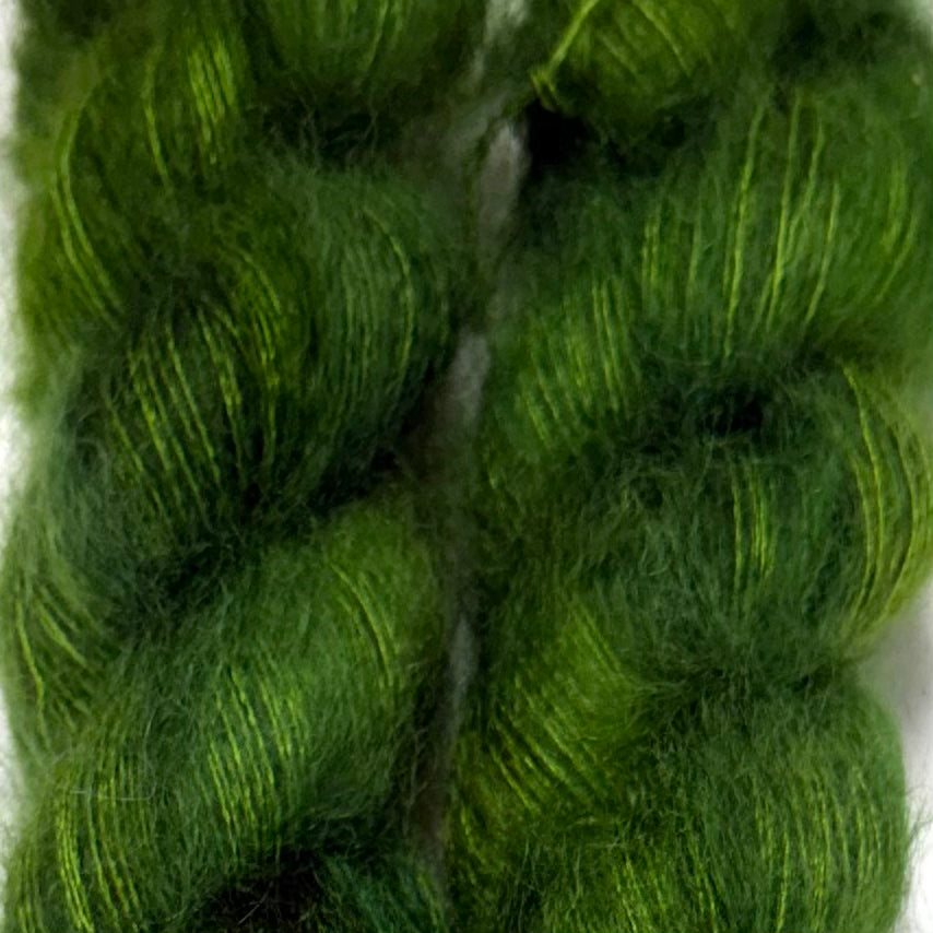 Delicious by Apple Fiber Studio. A close-up of bright green yarn skeins with subtle yellow-green highlights, filling the frame against a light background.