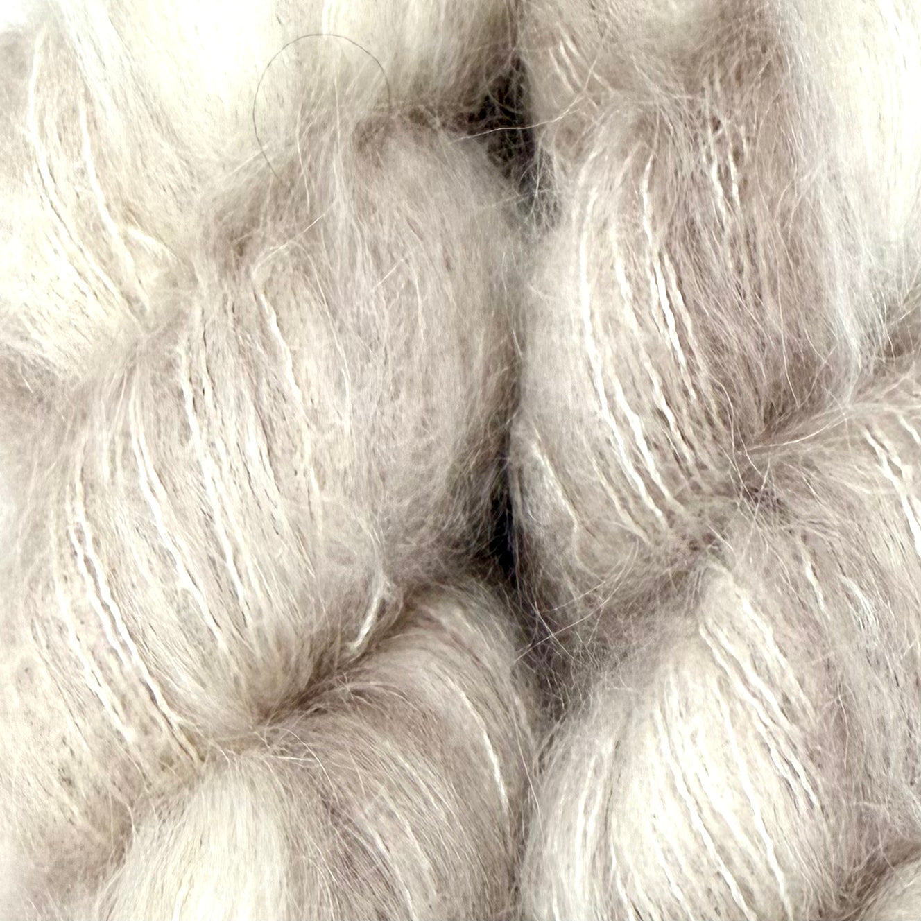 Close-up of fluffy, soft fibers in a pale warm gray-beige tone, filling the frame. Hand-dyed Cortland by Apple Fiber Studio in Alpaca and Silk at Apple Yarns.