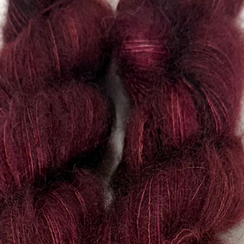 Delicious by Apple Fiber Studio. A close-up of dark burgundy hair extensions or a hair fiber blend, showing the texture and color of the strands.