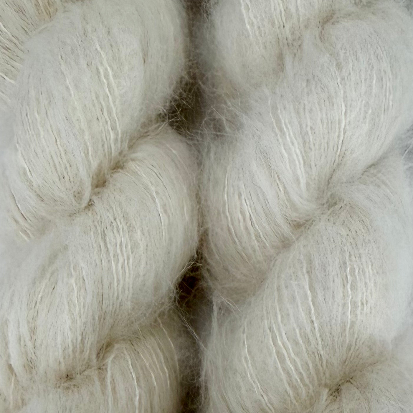 Close-up of soft, fluffy white yarn or fiber bales with a fuzzy, brushed texture filling the frame. Hand-dyed Cortland by Apple Fiber Studio in Alpaca and Silk at Apple Yarns.