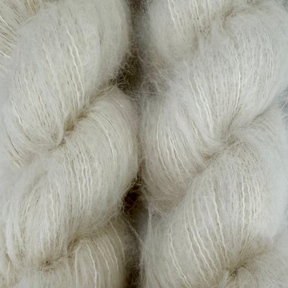 Close-up of soft, fluffy white yarn or fiber bales with a fuzzy, brushed texture filling the frame. Hand-dyed Cortland by Apple Fiber Studio in Alpaca and Silk at Apple Yarns.