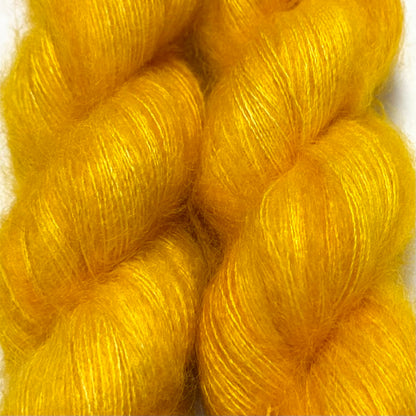Delicious by Apple Fiber Studio. Bright golden yellow yarn skeins with a soft, lustrous texture, photographed close-up against a white background.