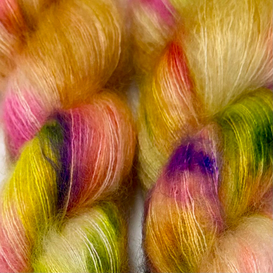 Delicious by Apple Fiber Studio. Close-up of soft, fuzzy yarn or fiber bundles in a pastel rainbow blend, including yellow, pink, orange, green, and purple tones.